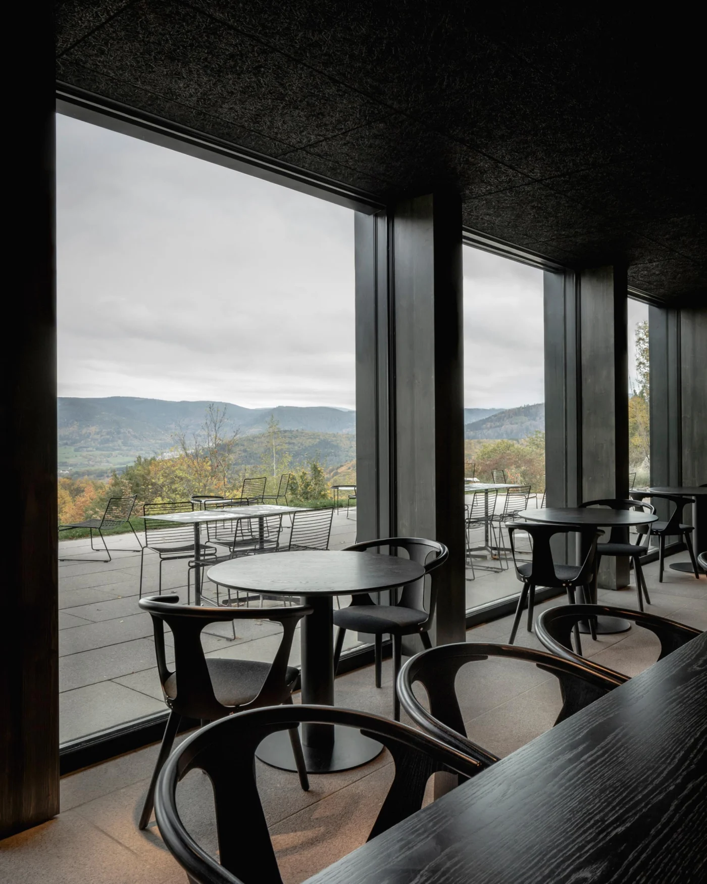 Restaurant with dark wood details and large windows onto the landscape