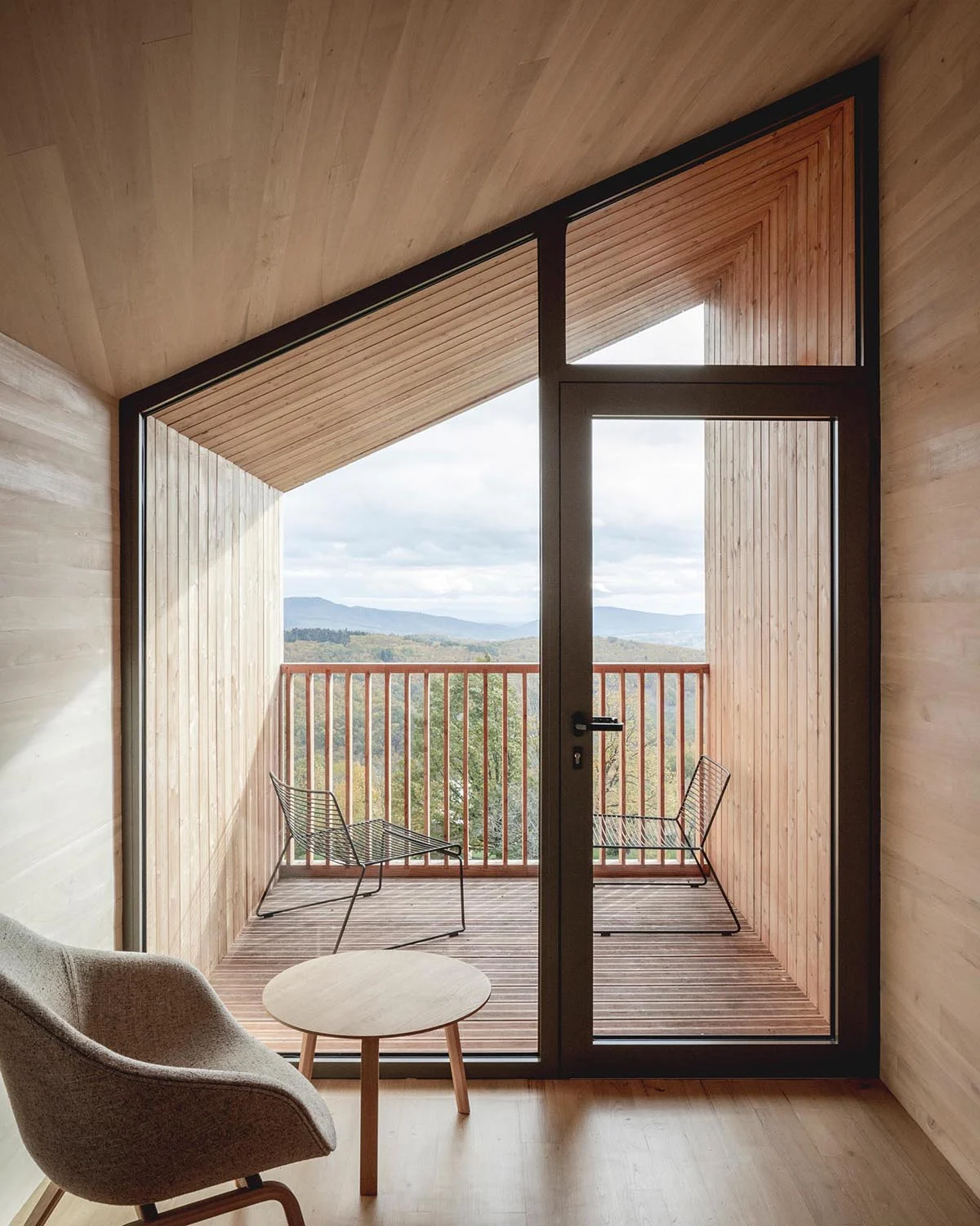 Cabin with a glass wall opening onto a small covered balcony