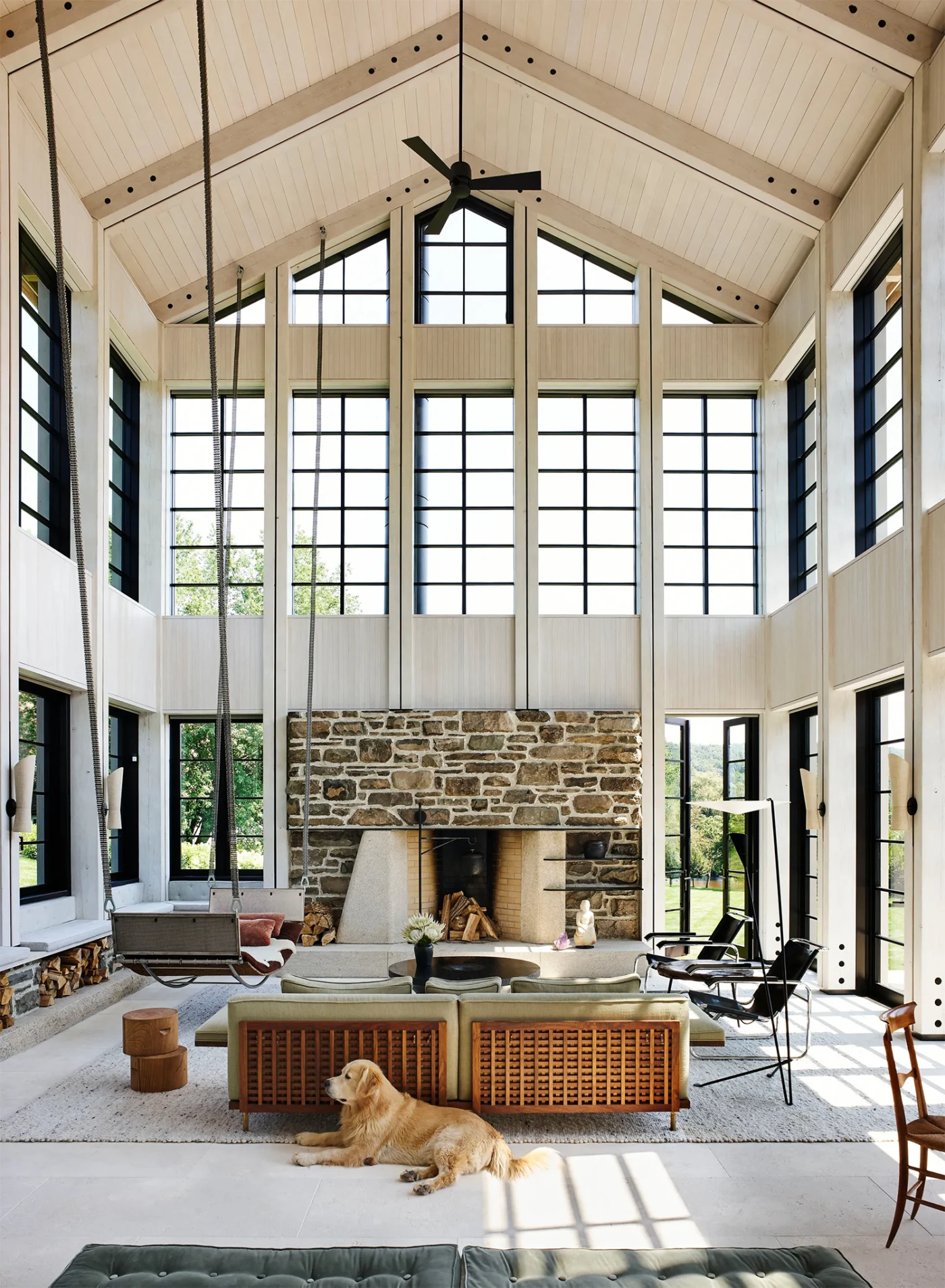 Double-height living room with a stone fireplace and white gabled ceiling