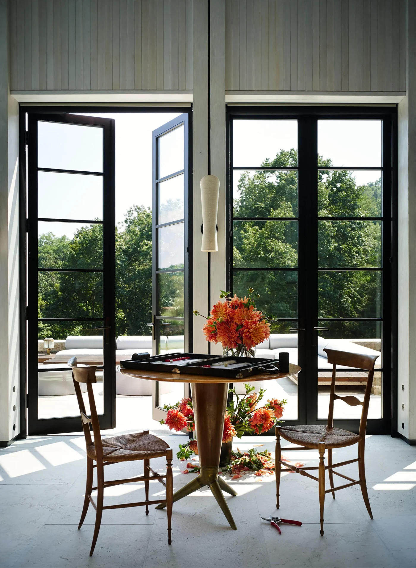 Tall glass doors opening from a sunlit room to the landscape