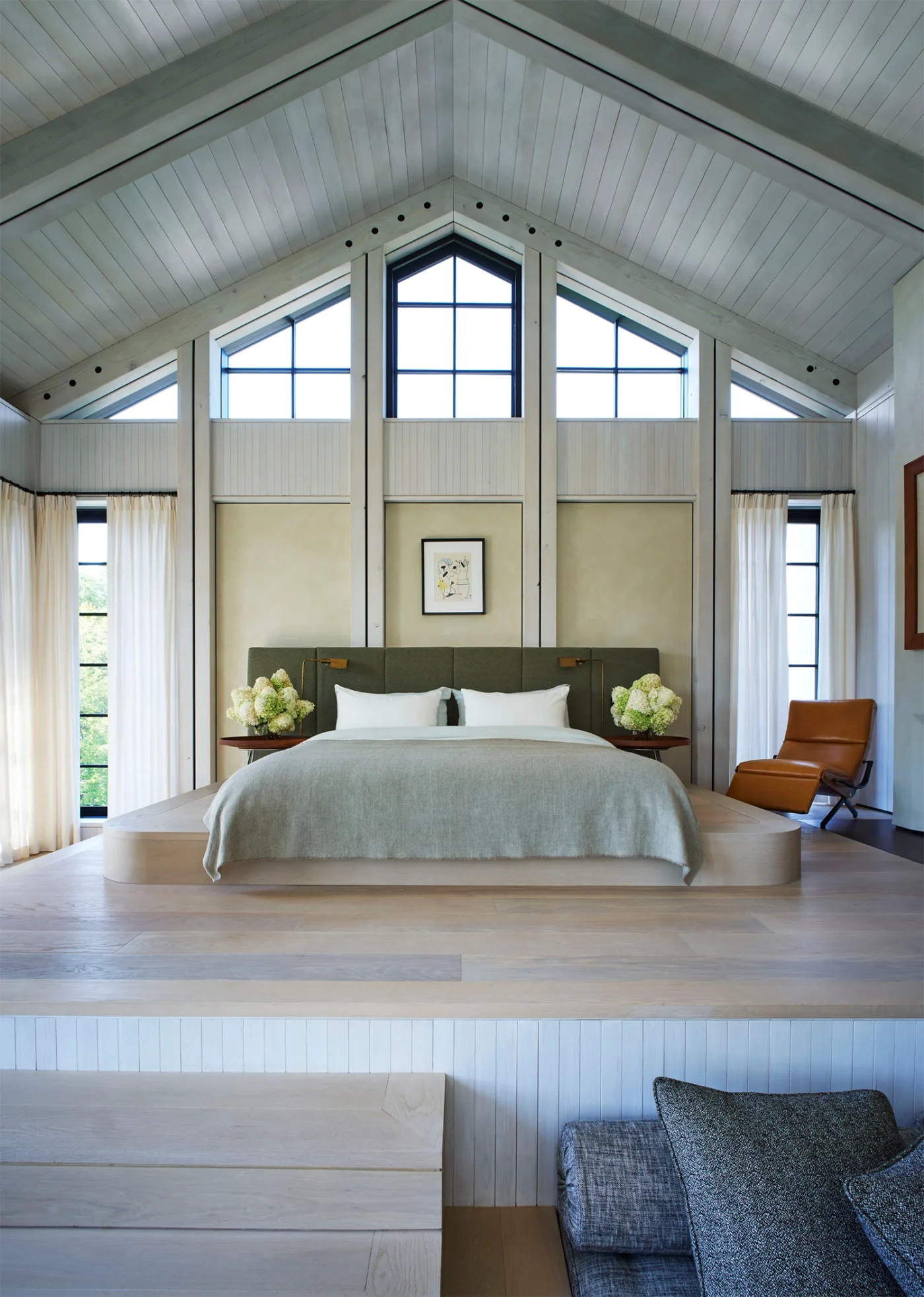 Bedroom beneath a white gabled ceiling with clerestory windows