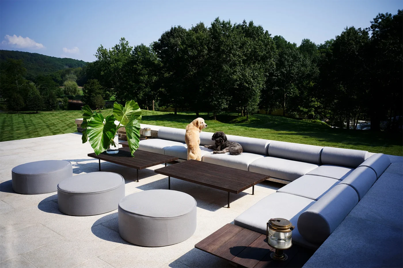 Outdoor lounge with a large sofa and round ottomans