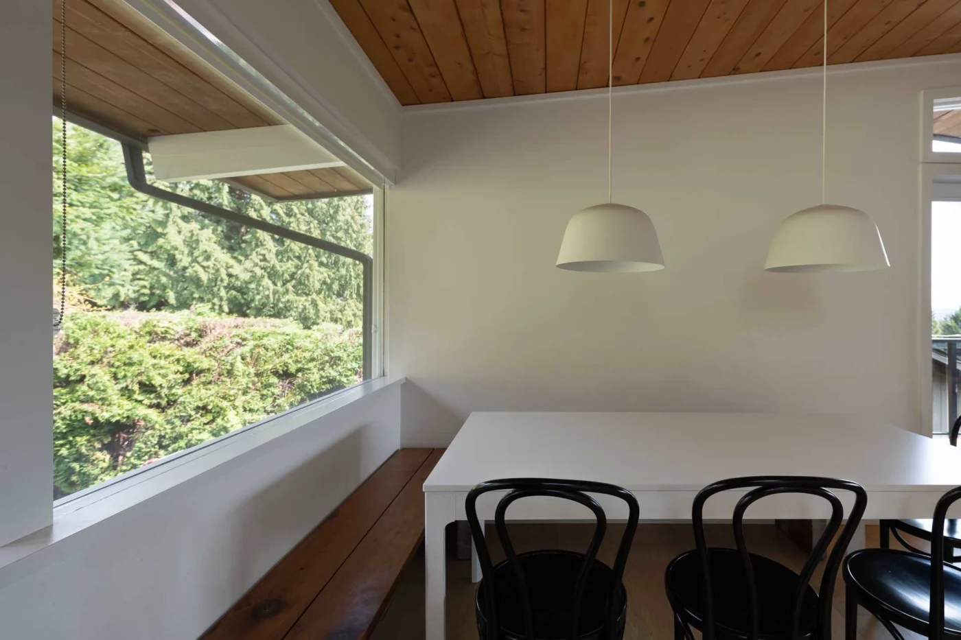 Open dining area with two white pendant lights over a white table
