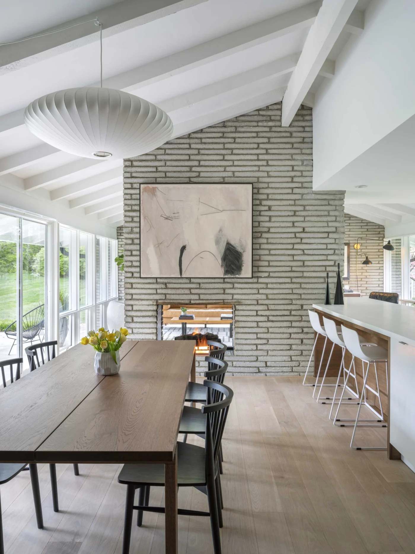 Large wood dining table beside the original double-sided brick fireplace