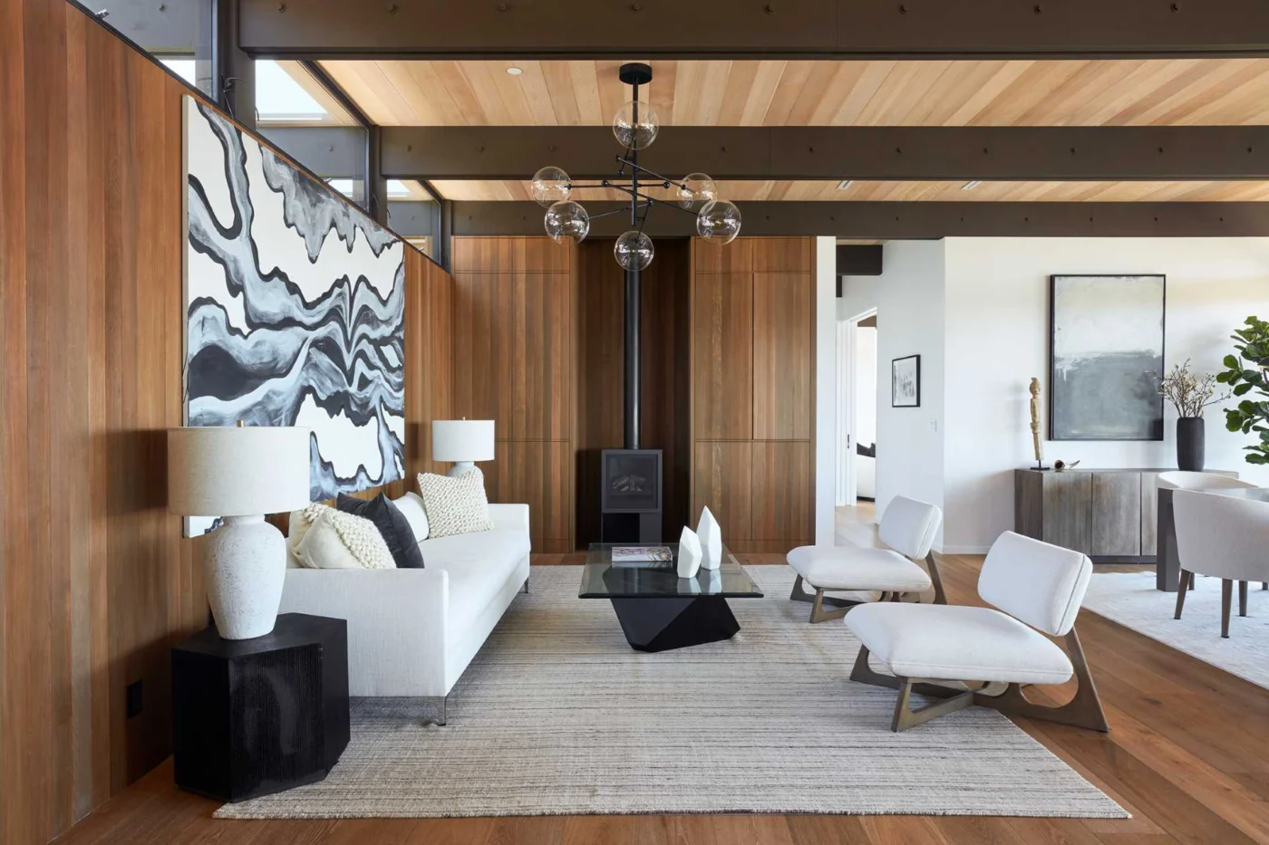 Main living room with wood-lined walls, built-in cabinets and a black fireplace