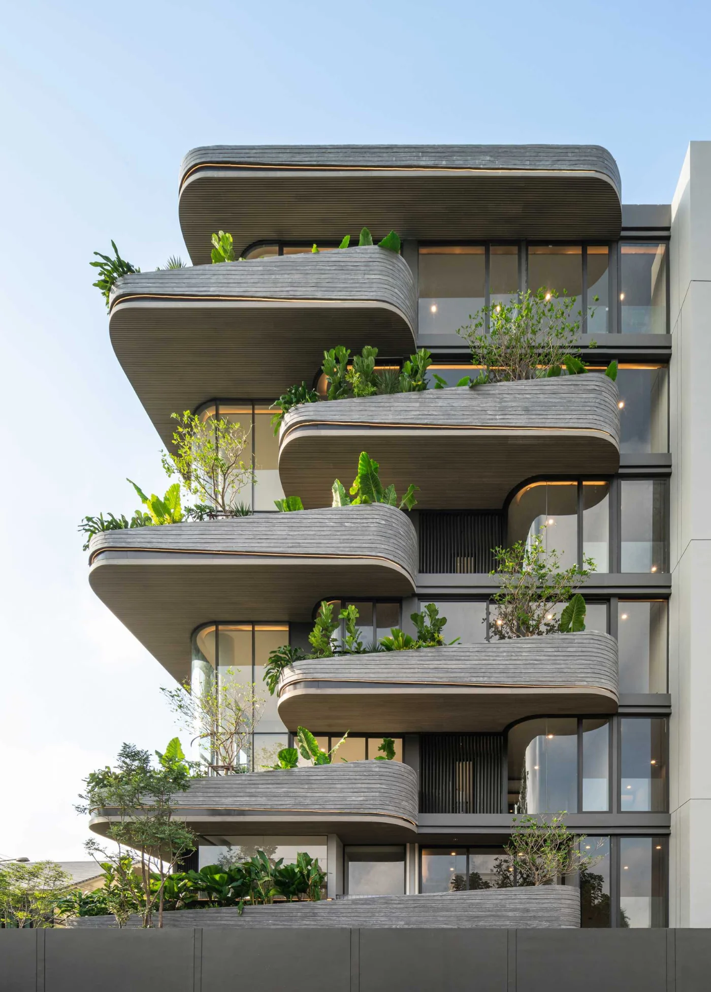 Rounded balconies with planters and railings on the Bangkok condo facade