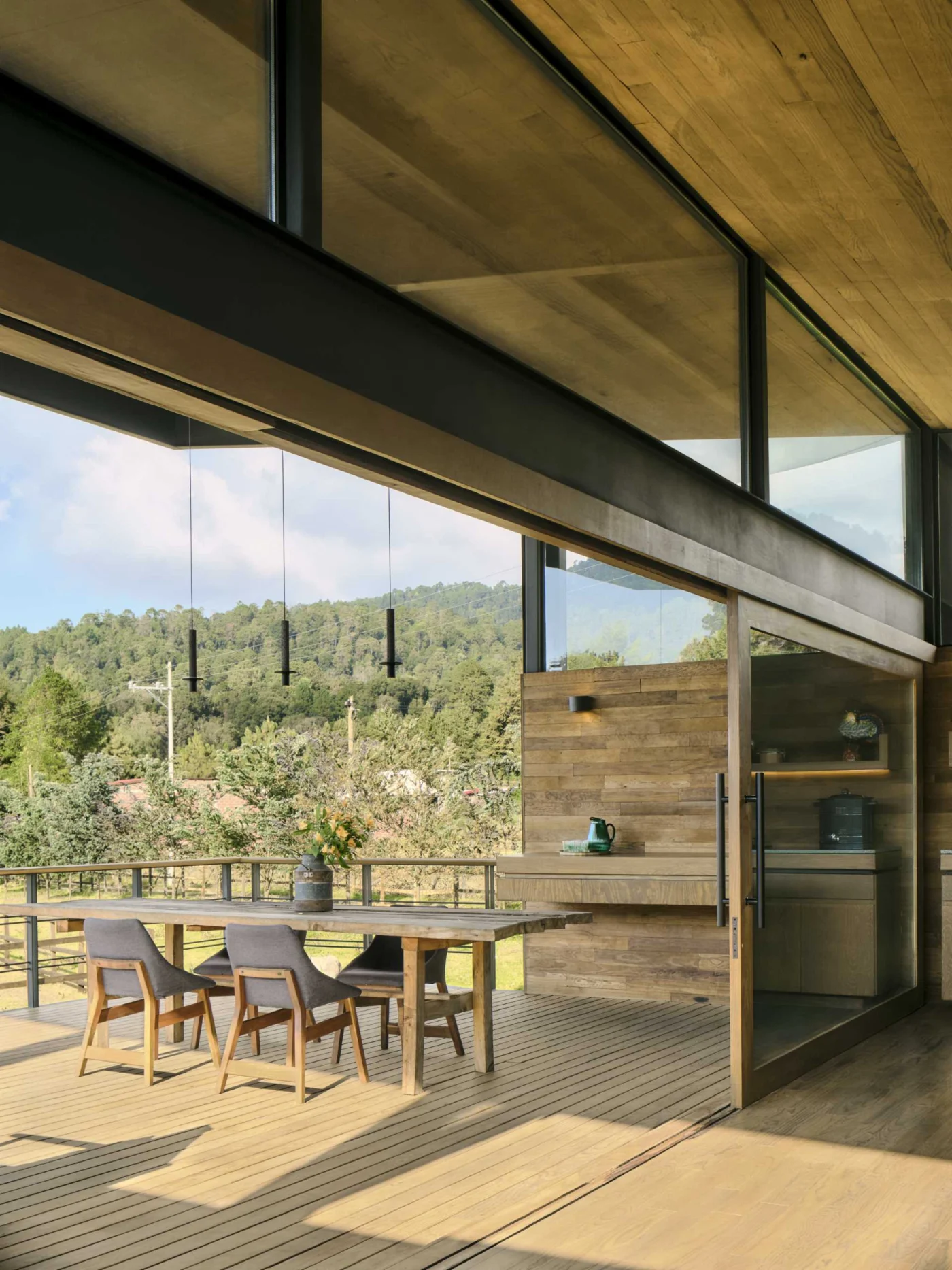 Terrace dining table under the sloping roof with forest views