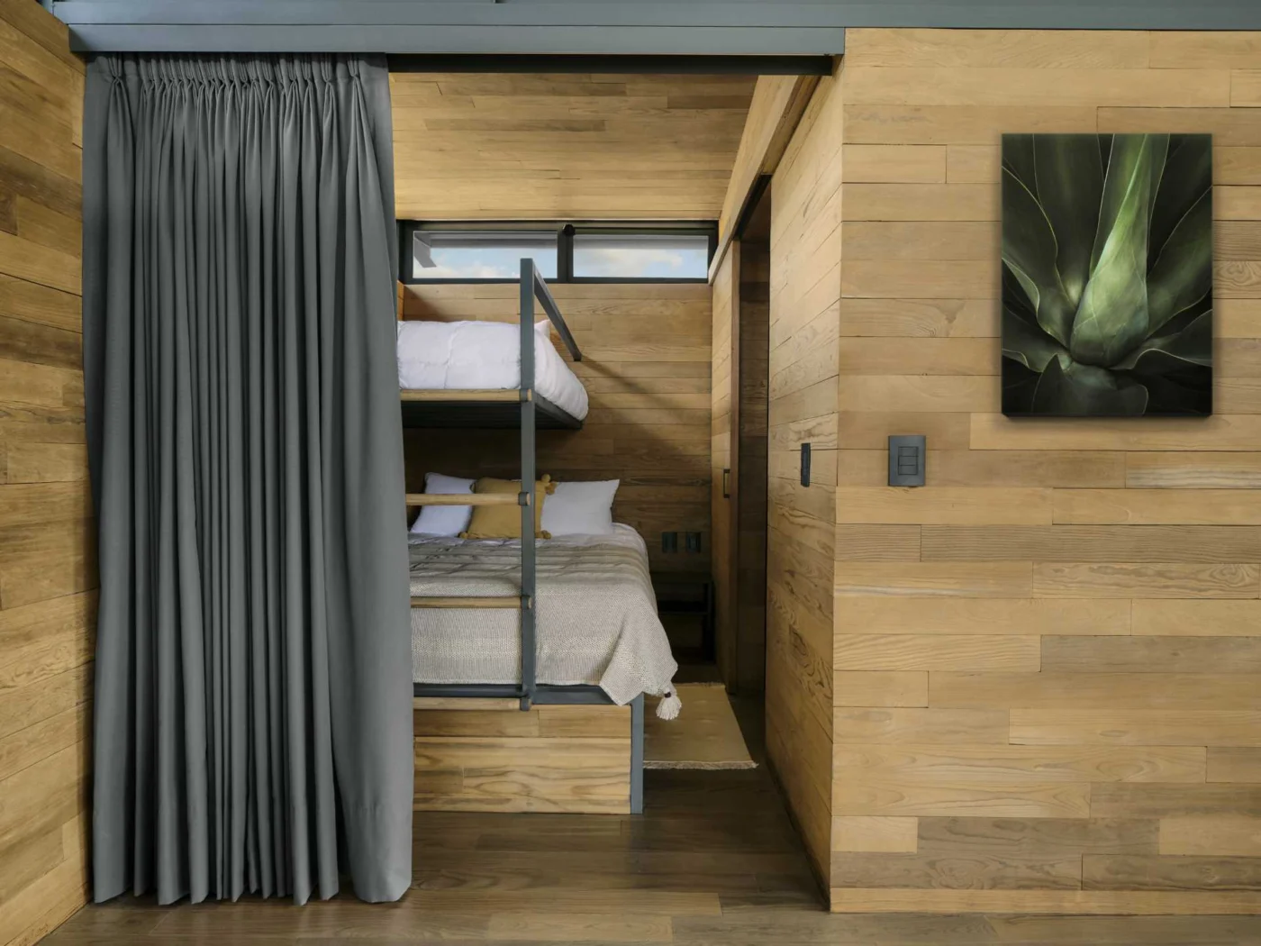 Bunk bed room lined in wood with a curtain for privacy