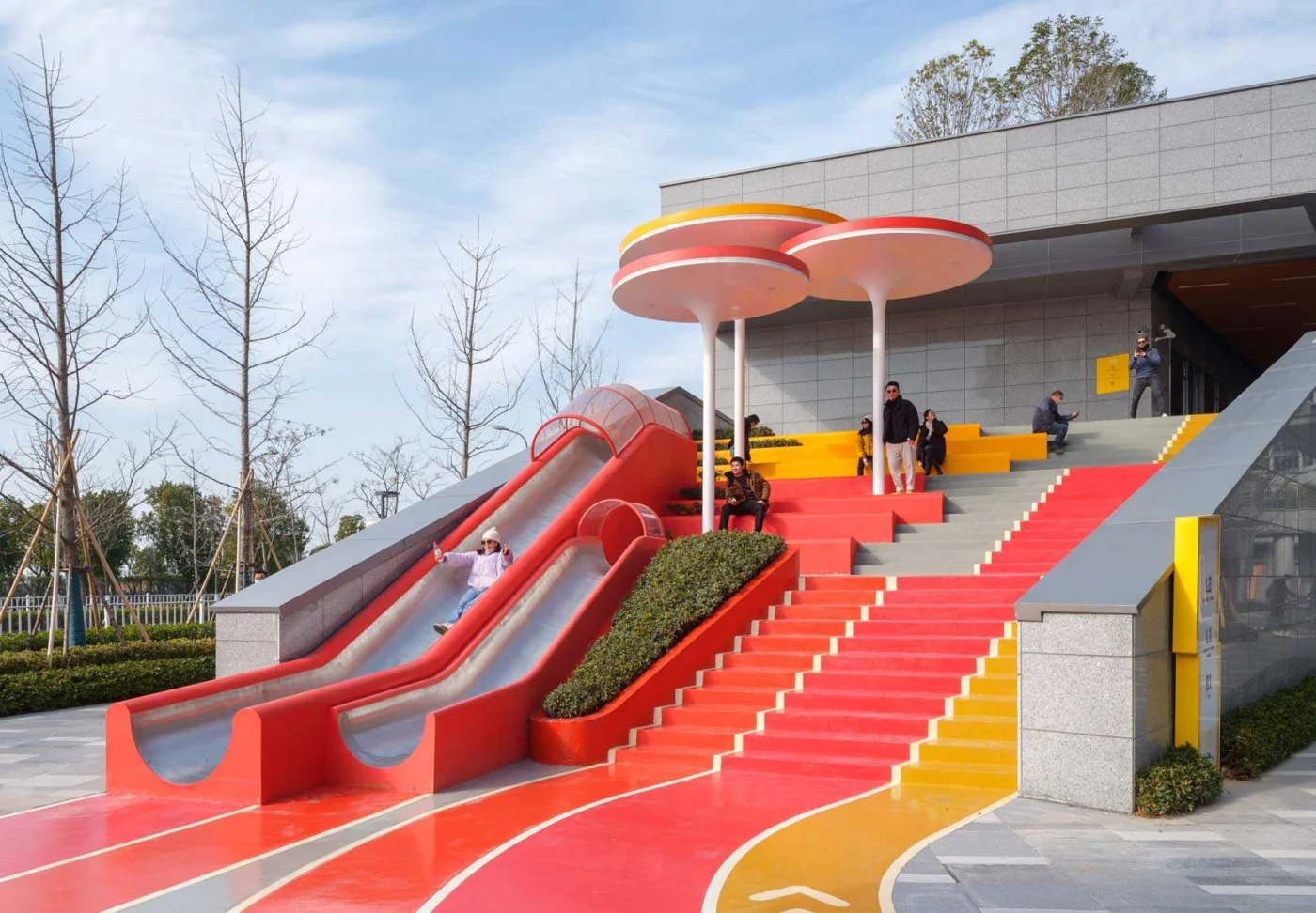 Red staircase with seating and slides under round canopies