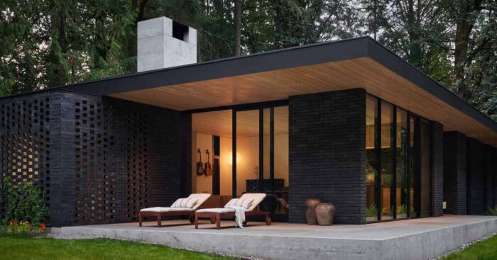 a-black-brick-exterior-is-consistent-with-the-dark-forest-surrounding-this-modern-home