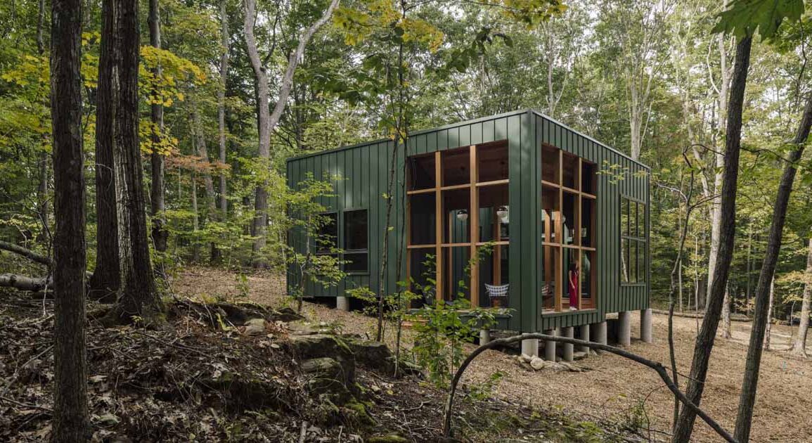 a-green-exterior-helps-this-cabin-blend-into-the-forest