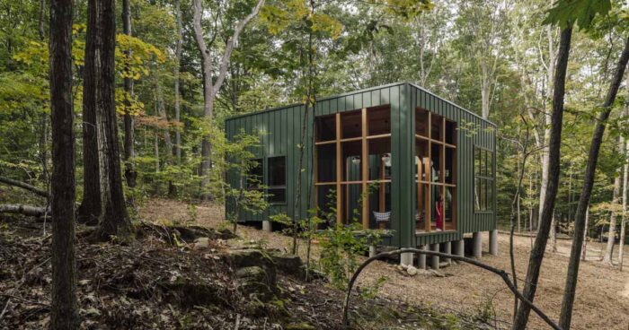a-green-exterior-helps-this-cabin-blend-into-the-forest