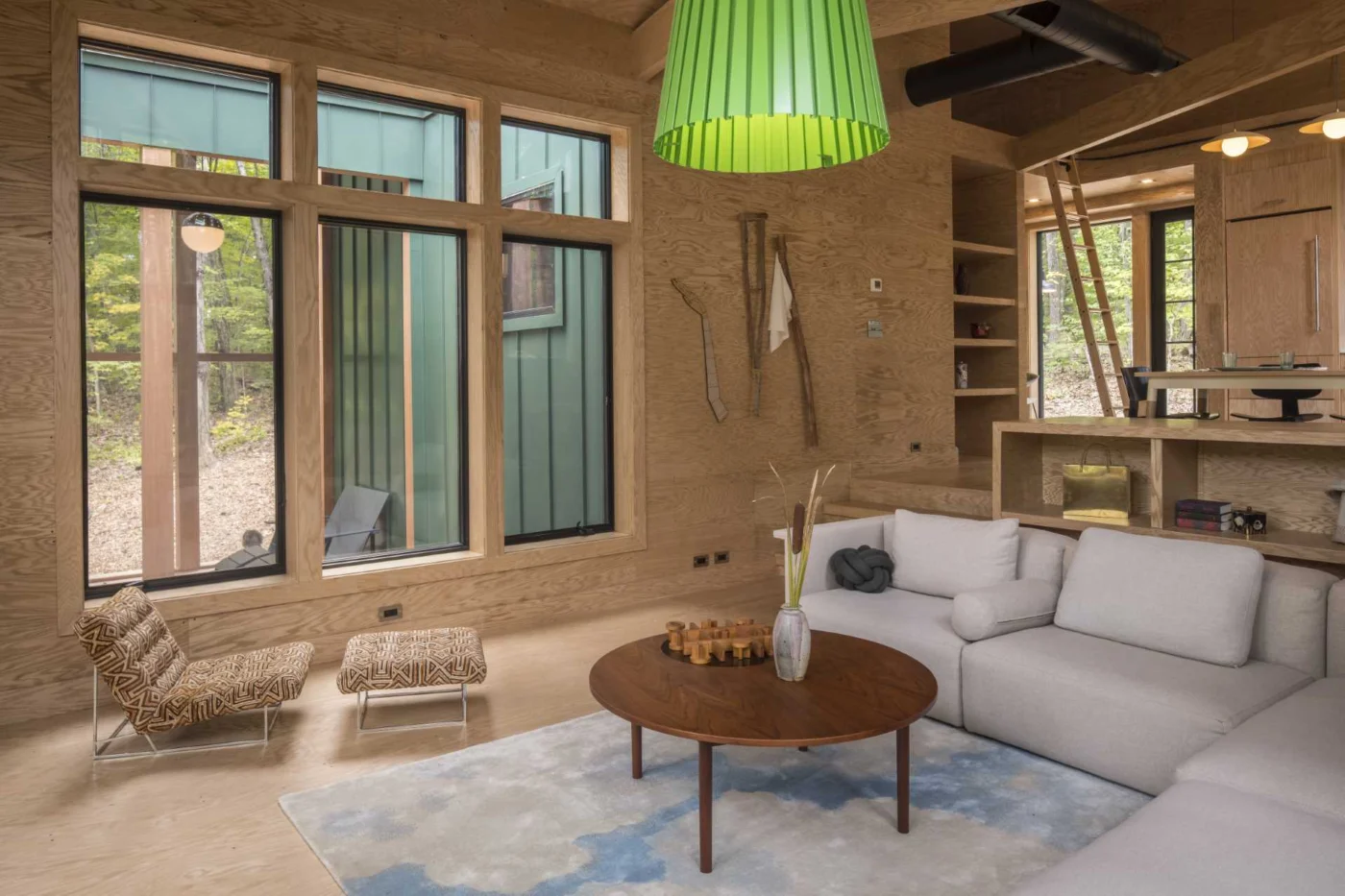 Wood-lined living room with a sofa, round table and green pendant