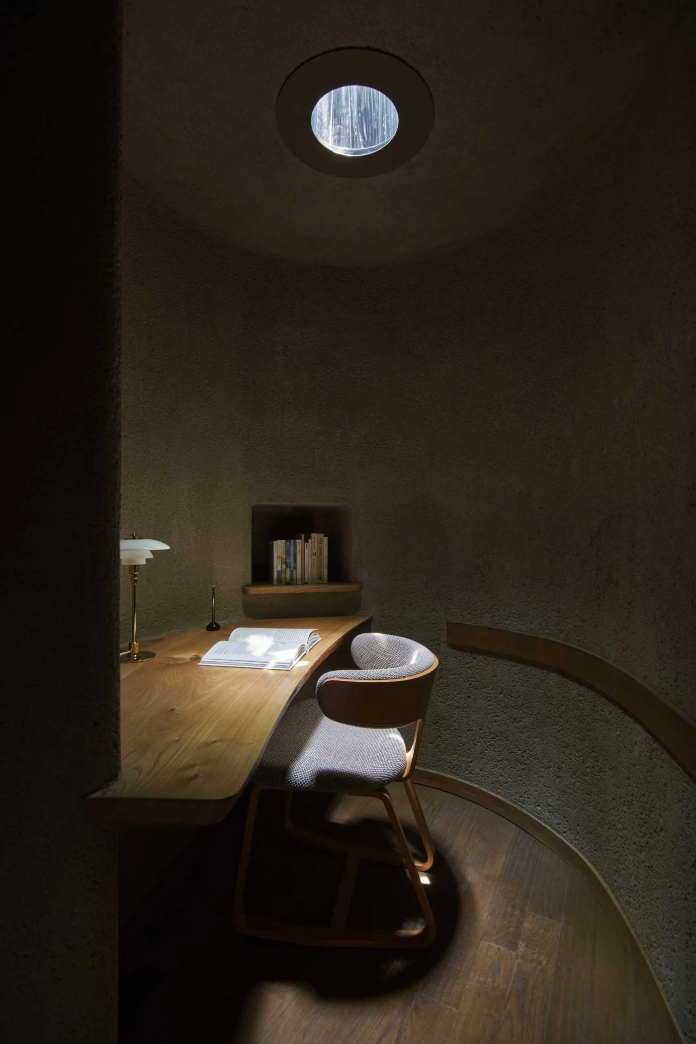 Small reading room with a desk lit by a round skylight