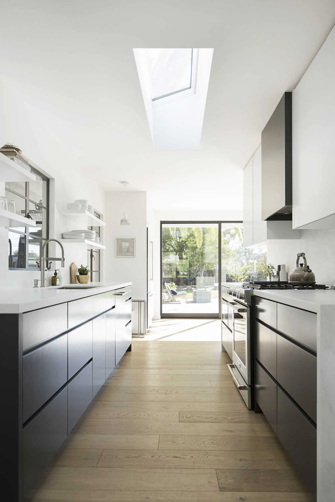 Black and white kitchen lit by a skylight above