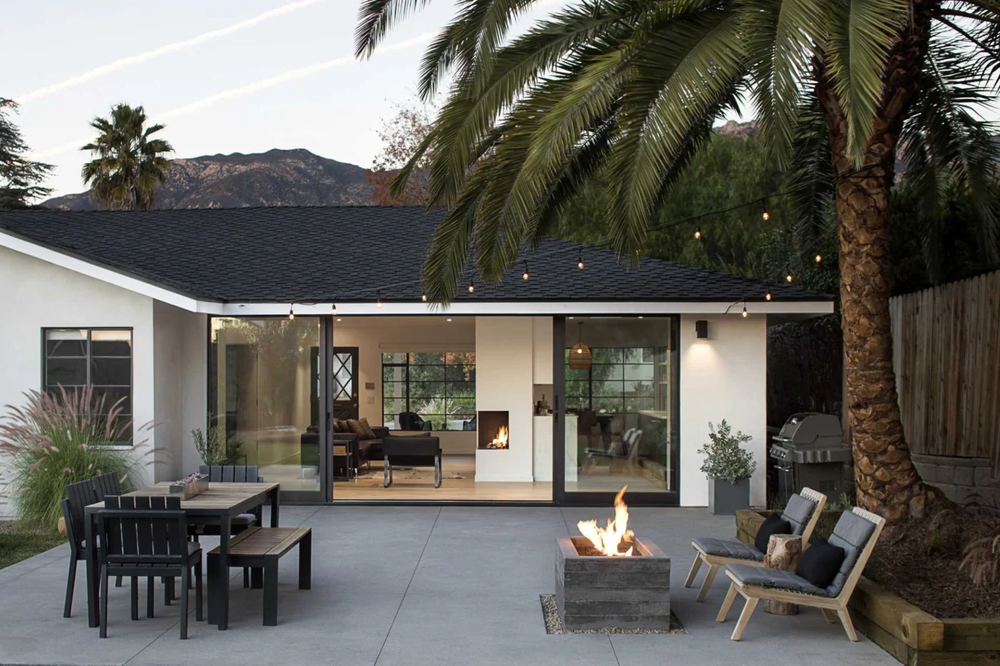 Rear patio with outdoor dining, a fire pit and a large glass sliding wall