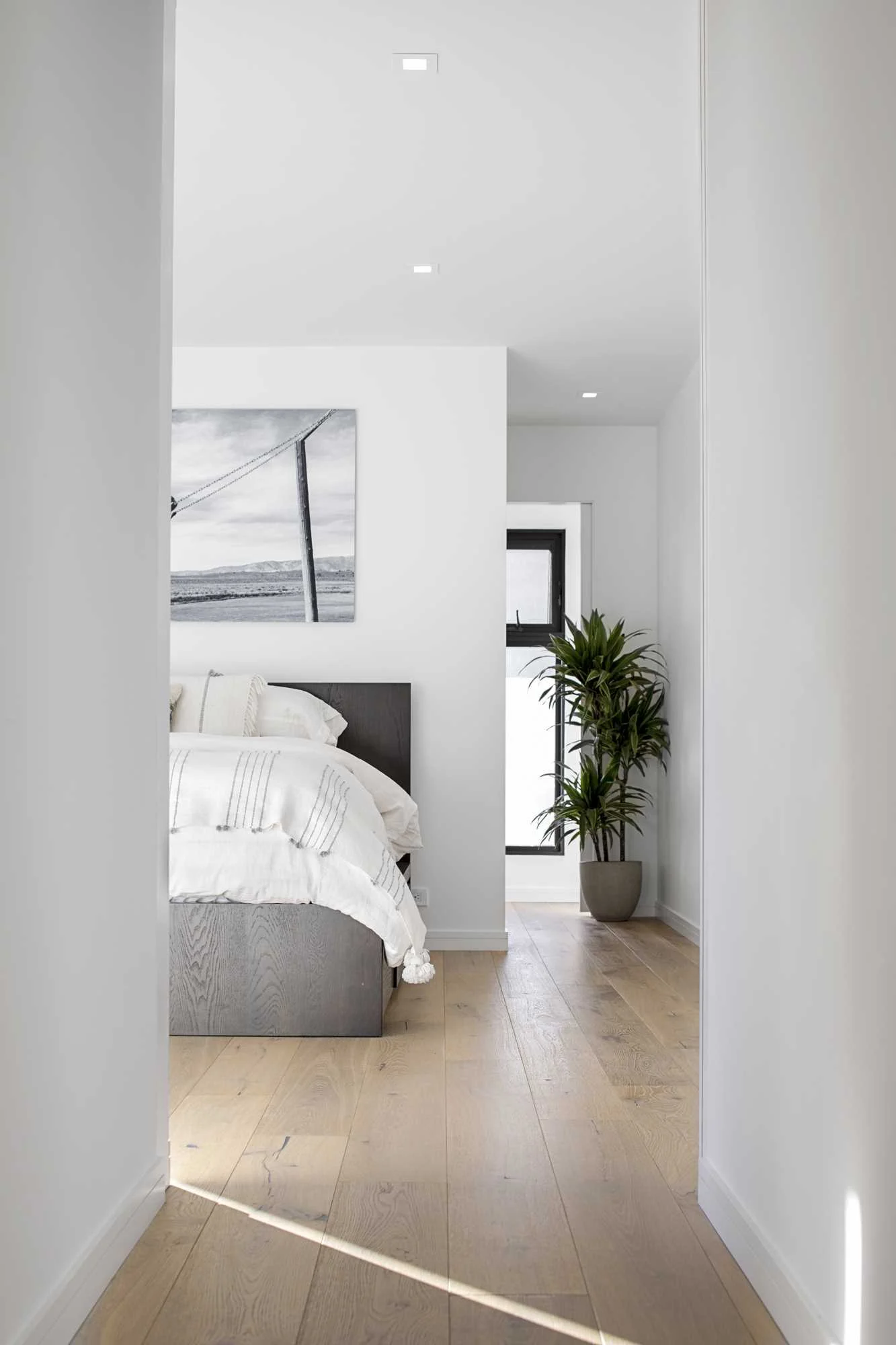 Minimal bedroom with white walls and warm wood floors