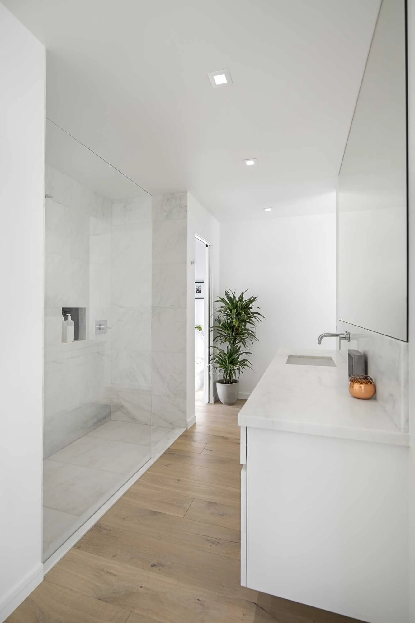 Bathroom with a glass walk-in shower opposite a white vanity