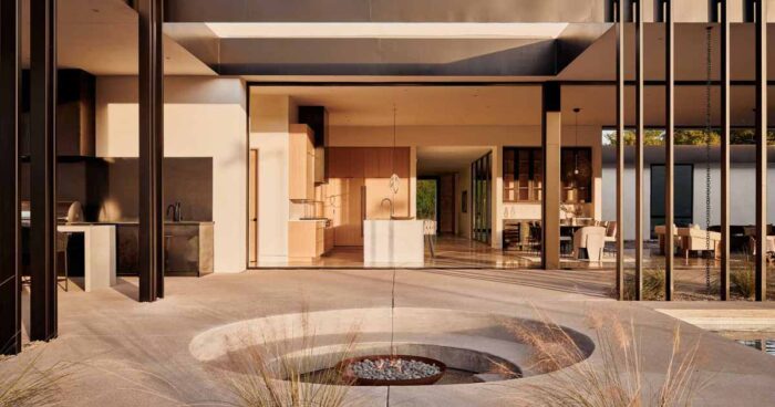 a-circular-sunken-firepit-is-nestled-into-the-desert-landscape-of-this-home