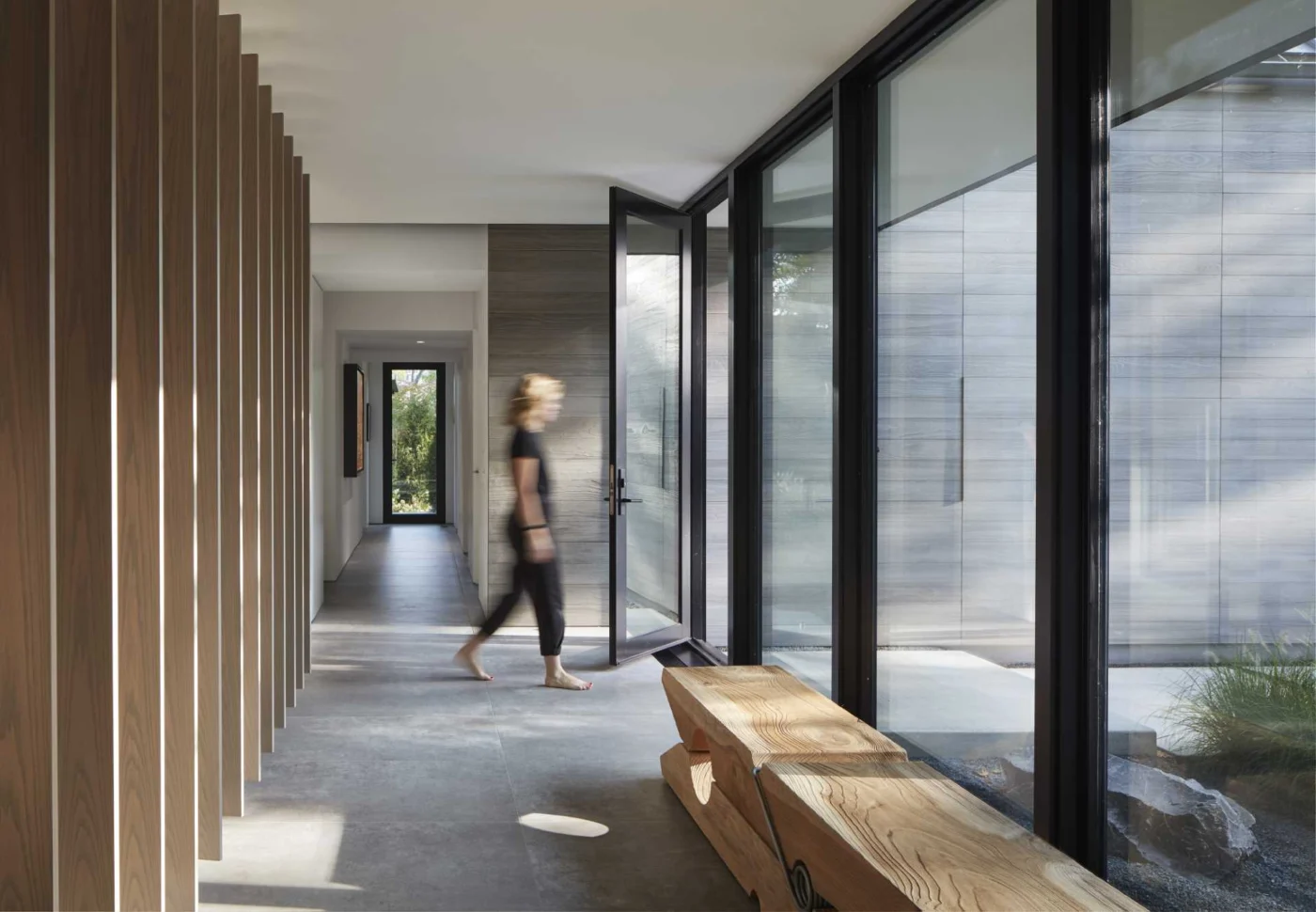Glazed breezeway with floor-to-ceiling glass and a wood-lined wall