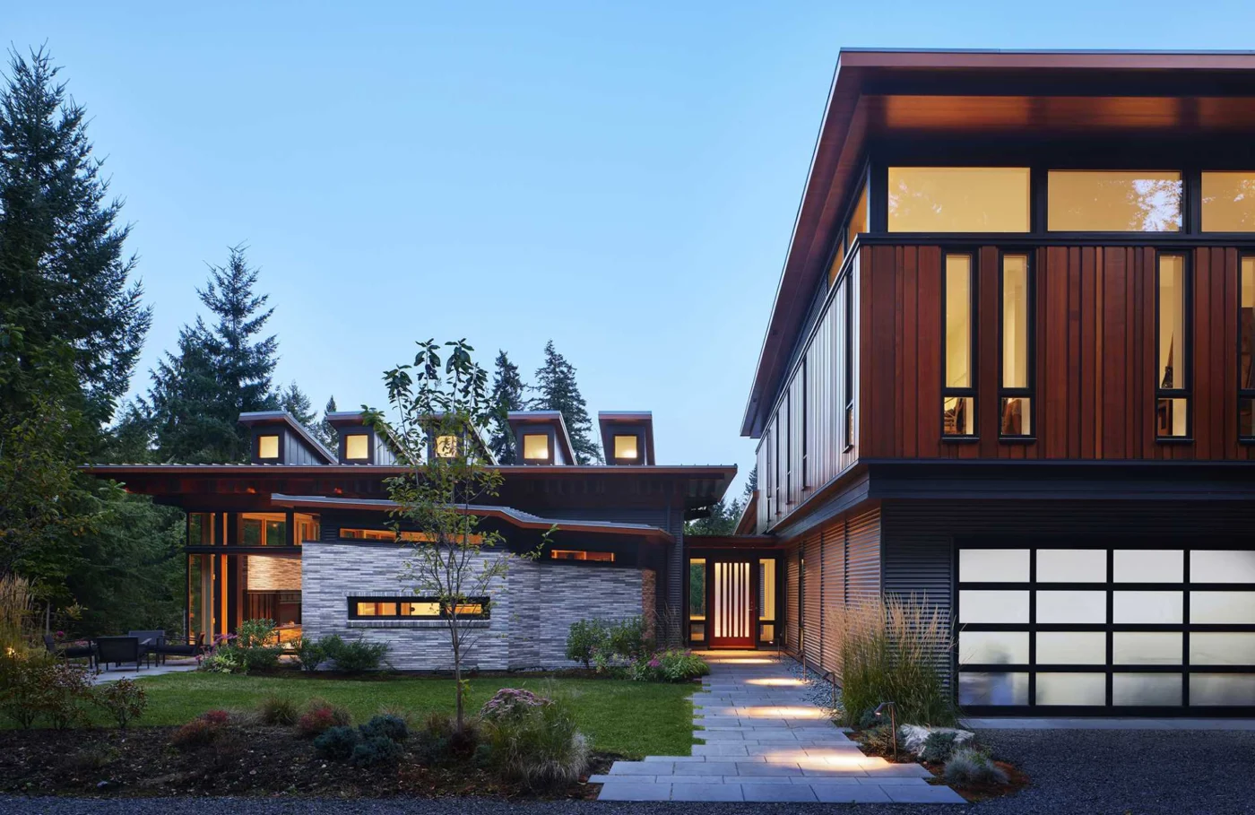 Entrance court with wood cladding, stone and a glass garage door