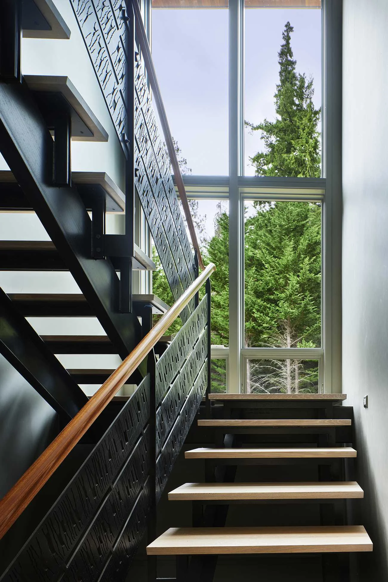 Steel and wood stair beside double-height windows