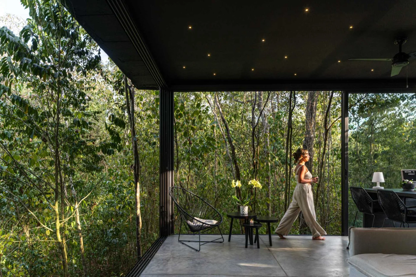 Open interior of a glass house looking out to the jungle