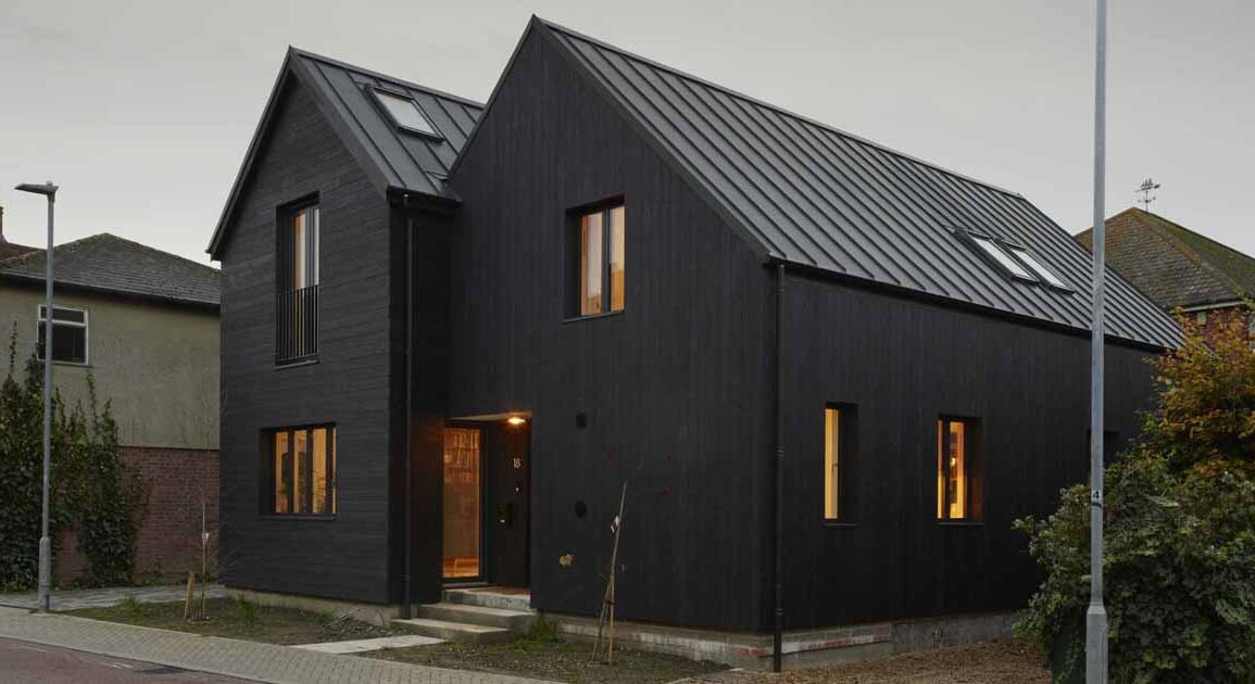 the-black-exterior-of-this-home-leads-to-a-pink-kitchen-inside