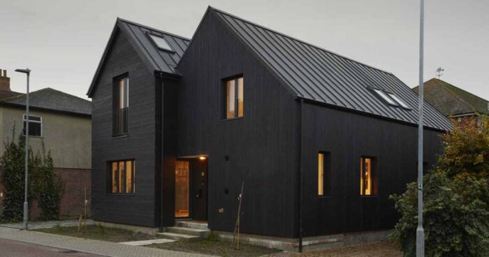 the-black-exterior-of-this-home-leads-to-a-pink-kitchen-inside