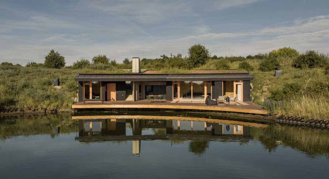 this-small-home-with-a-green-roof-curves-around-a-pond