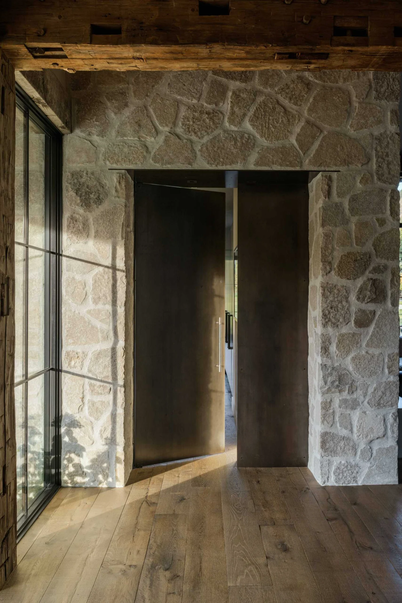 Entry with steel doors, stone walls, antique flooring and heavy timber beams