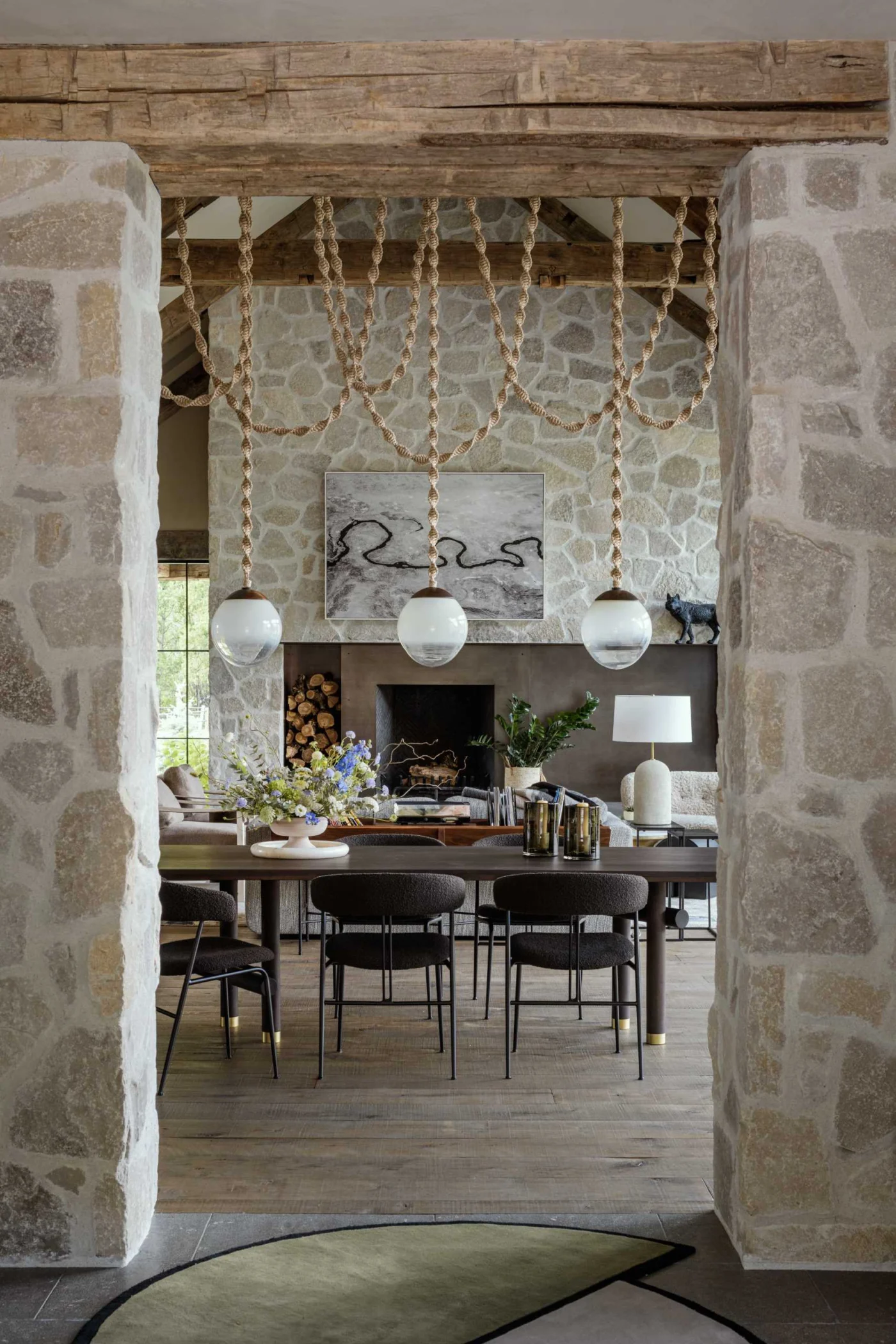 Stone-framed opening with custom light fixtures between the living area and kitchen