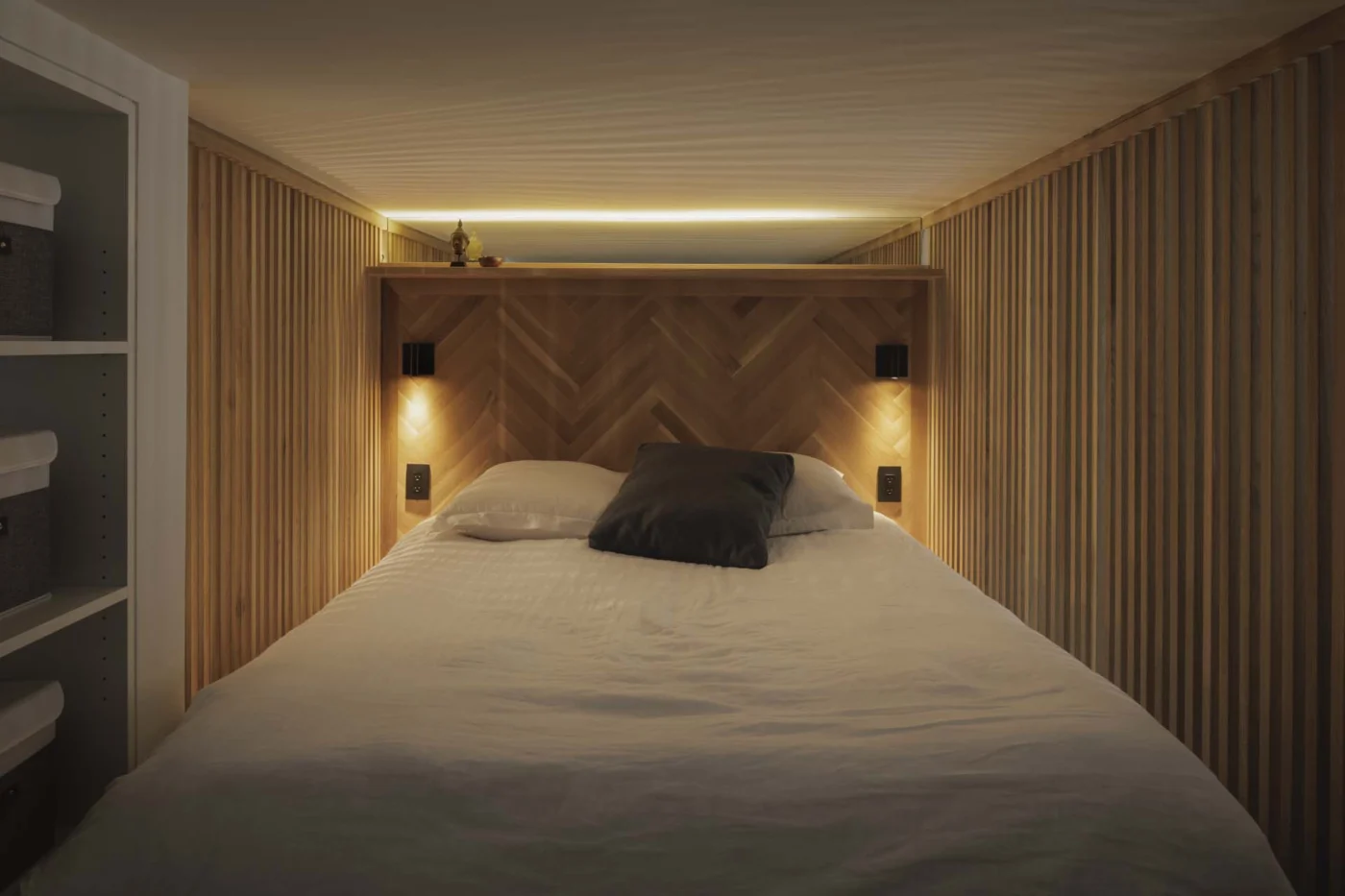 Lofted bedroom lined with slats and a herringbone headboard