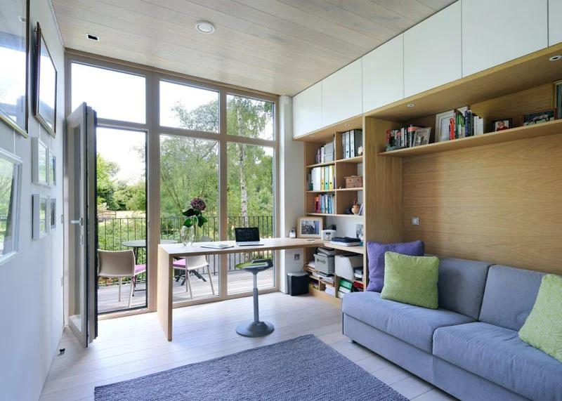 Home office with built-in shelves, a sofa and doors to a deck