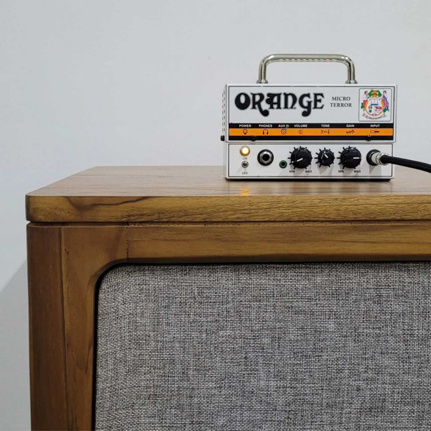 Solid teak amp cabinet with rounded corners and a framed speaker driver