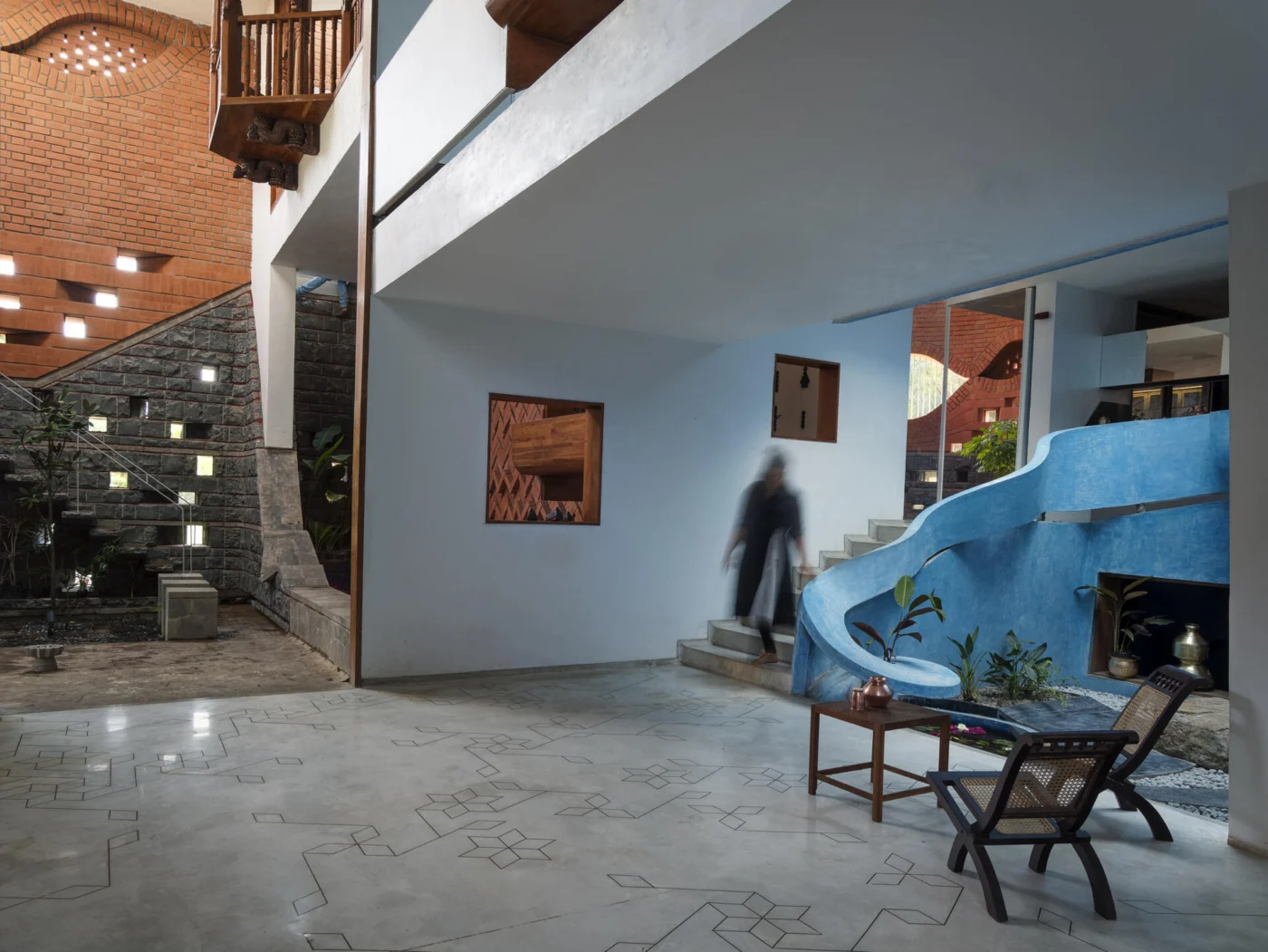 Hall with smooth blue lime stucco walls and a sculptural staircase