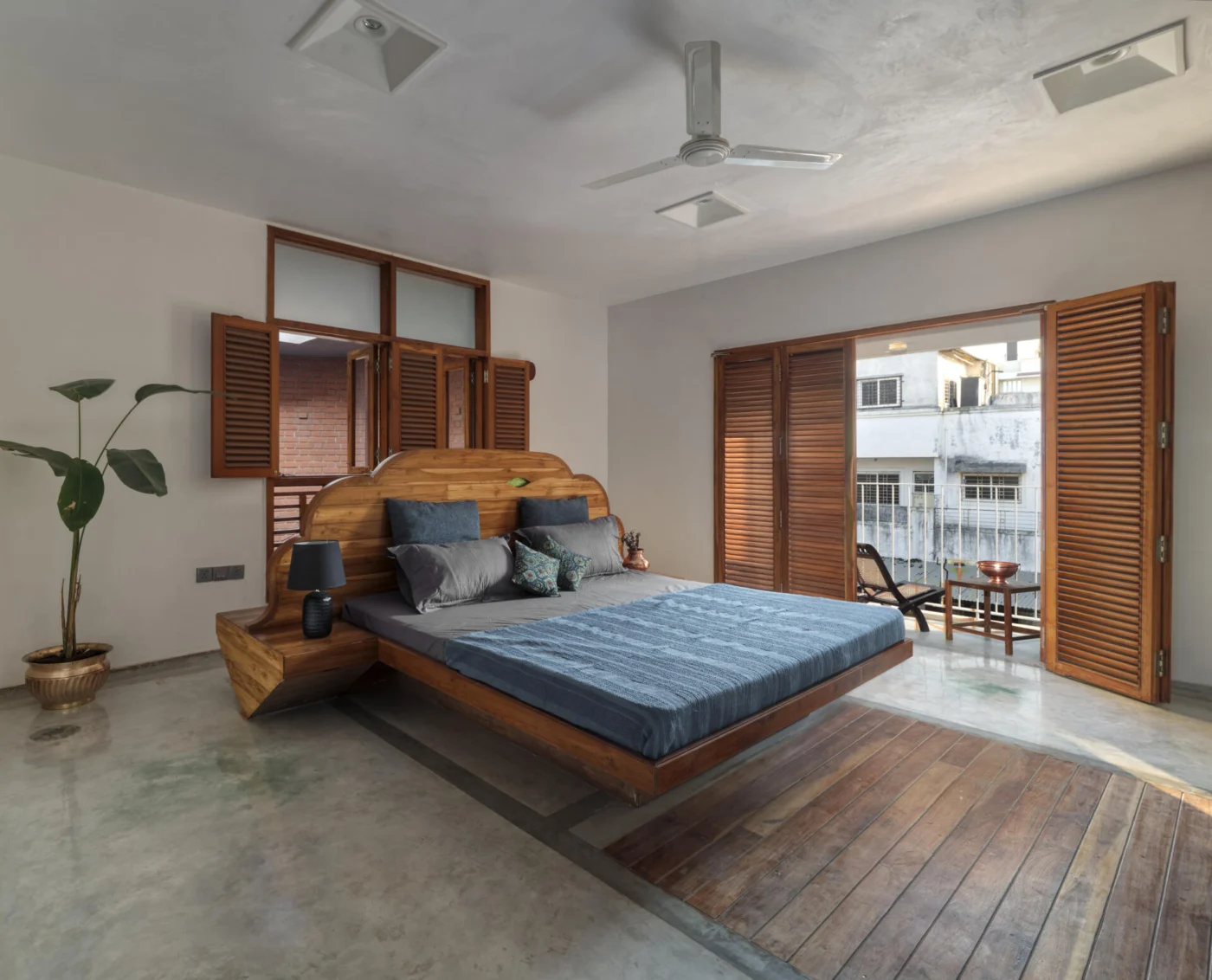 Bedroom with wood shutters, a wood bed and a concrete floor