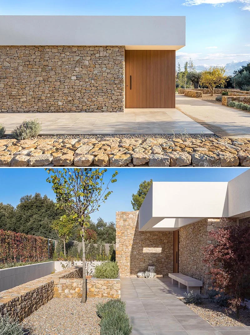 Stone facade with a wood front door under a smooth white upper volume
