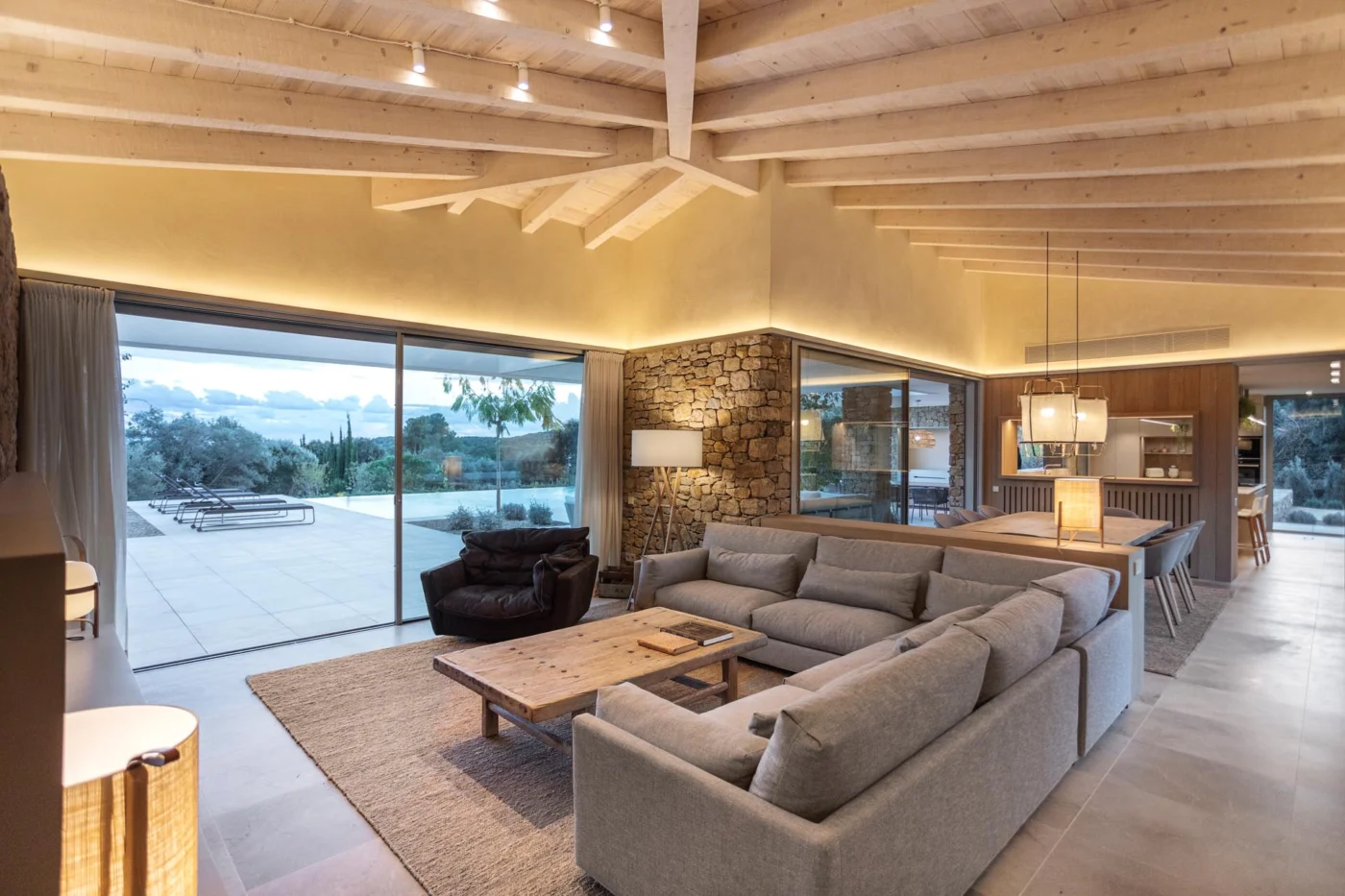 Open-plan living room under a pale timber ceiling with views to the pool