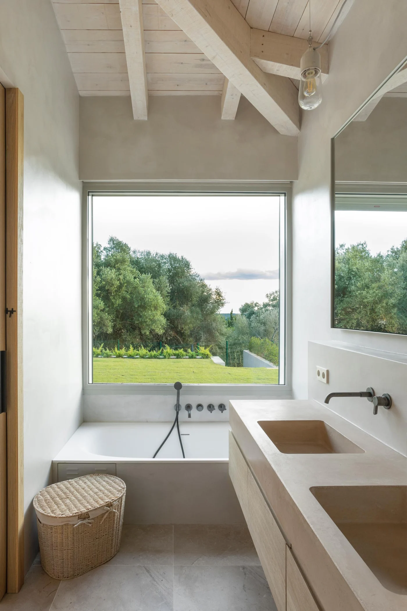 Bathroom with a built-in bathtub beneath a window and a wood vanity